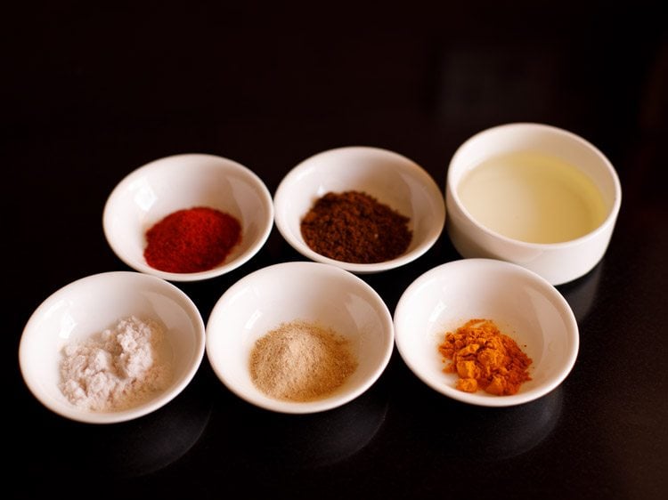 spice powders and oil kept in small white bowls
