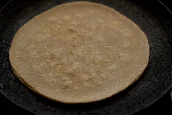 frying aloo paratha after flipping the first time - there are very faint bubbles beginning to appear.