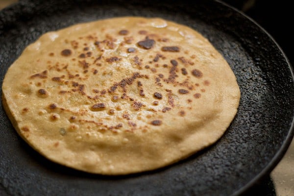 cooked aloo paratha on skillet.