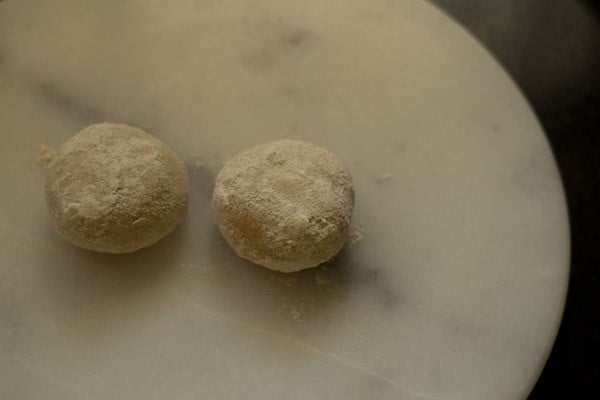 two small balls of paratha dough on a marble slab.