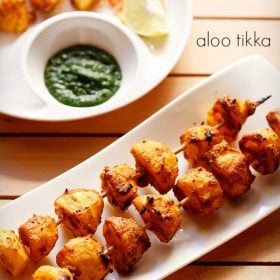 tandoori aloo tikka served on a white rectangular platter with a bowl of green chutney on the top left side and text layovers.