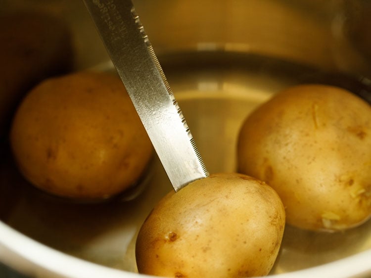 checking the doneness of potatoes with a knife.