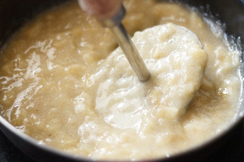 Top shot of mashed bananas in pot with masher for banana bread