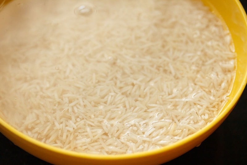 Top shot of rice soaking in water in yellow bowl
