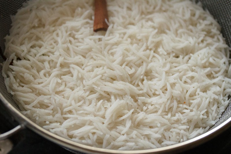 Top shot of cooked rice in a strainer for veg biryani recipe