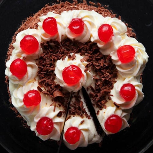 overhead shot of black forest cake on a black plate with a slice being removed