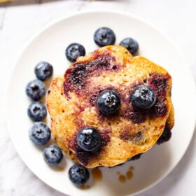 top shot of blueberry pancakes with blueberries in a white plate.