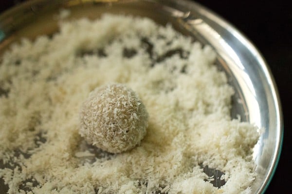 desiccated coconut coated ladoo on a plate filled with desiccated coconut