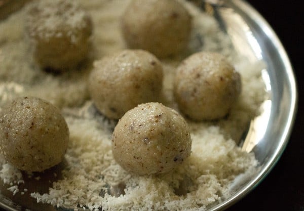 five coconut ladoo placed on desiccated coconut in a plate