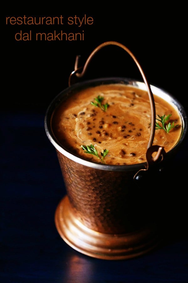 dal makhani garnished with coriander leaves and served in a fancy copper bucket with text layovers.