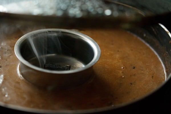 the steel bowl with the smoking charcoal kept on top of the dal makhani in the pan