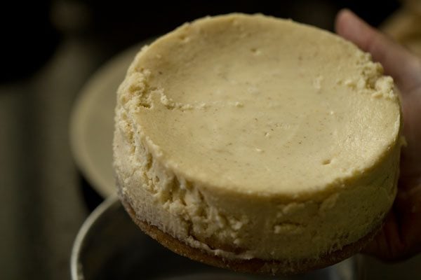 hand removing cheesecake from pan