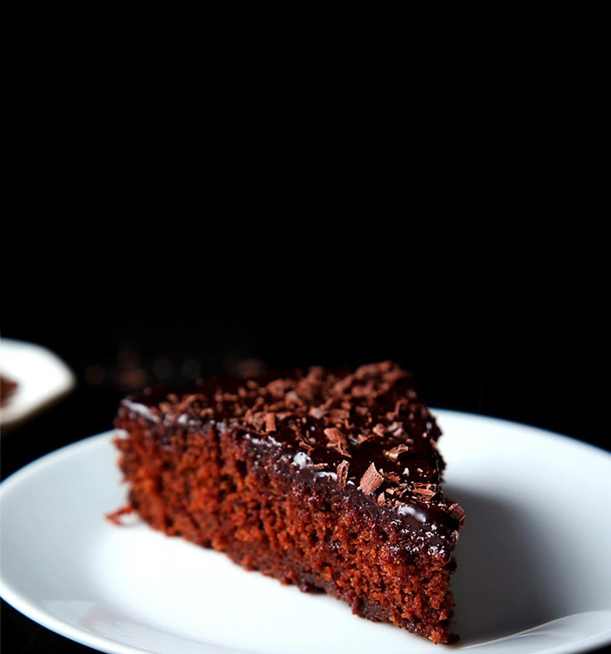 A triangular wedge of eggless chocolate cake on a white plate