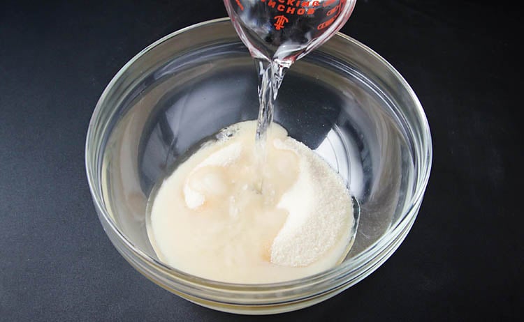 water being added in a small bowl containing sugar