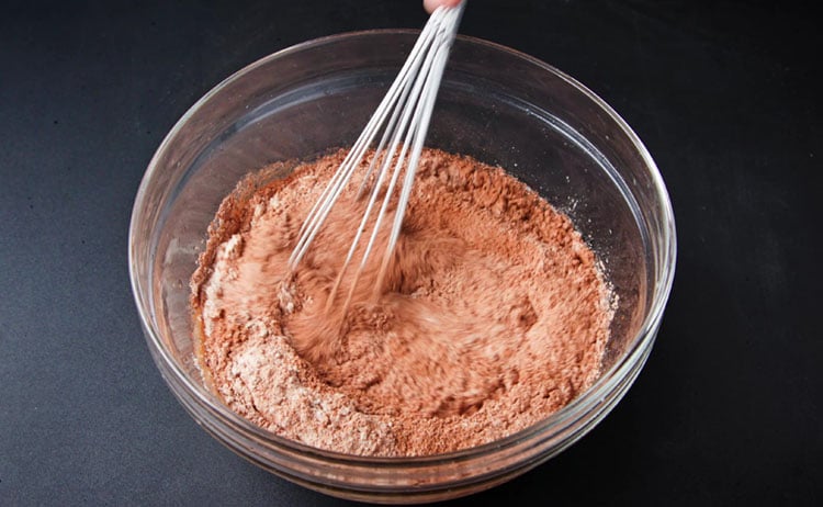 mixing eggless chocolate cake batter with a whisk