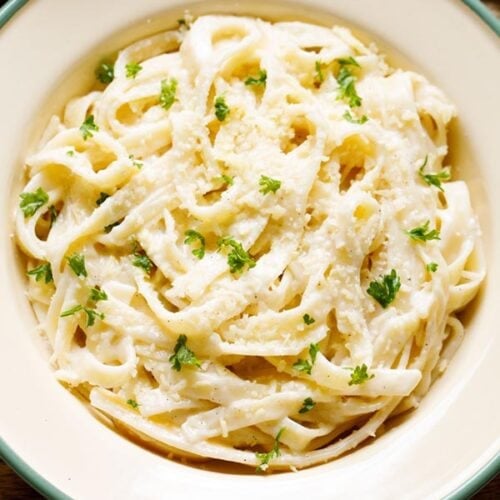 fettuccine alfredo sprinkled with grated parmesan and chopped parsley filled in a deep dish plate