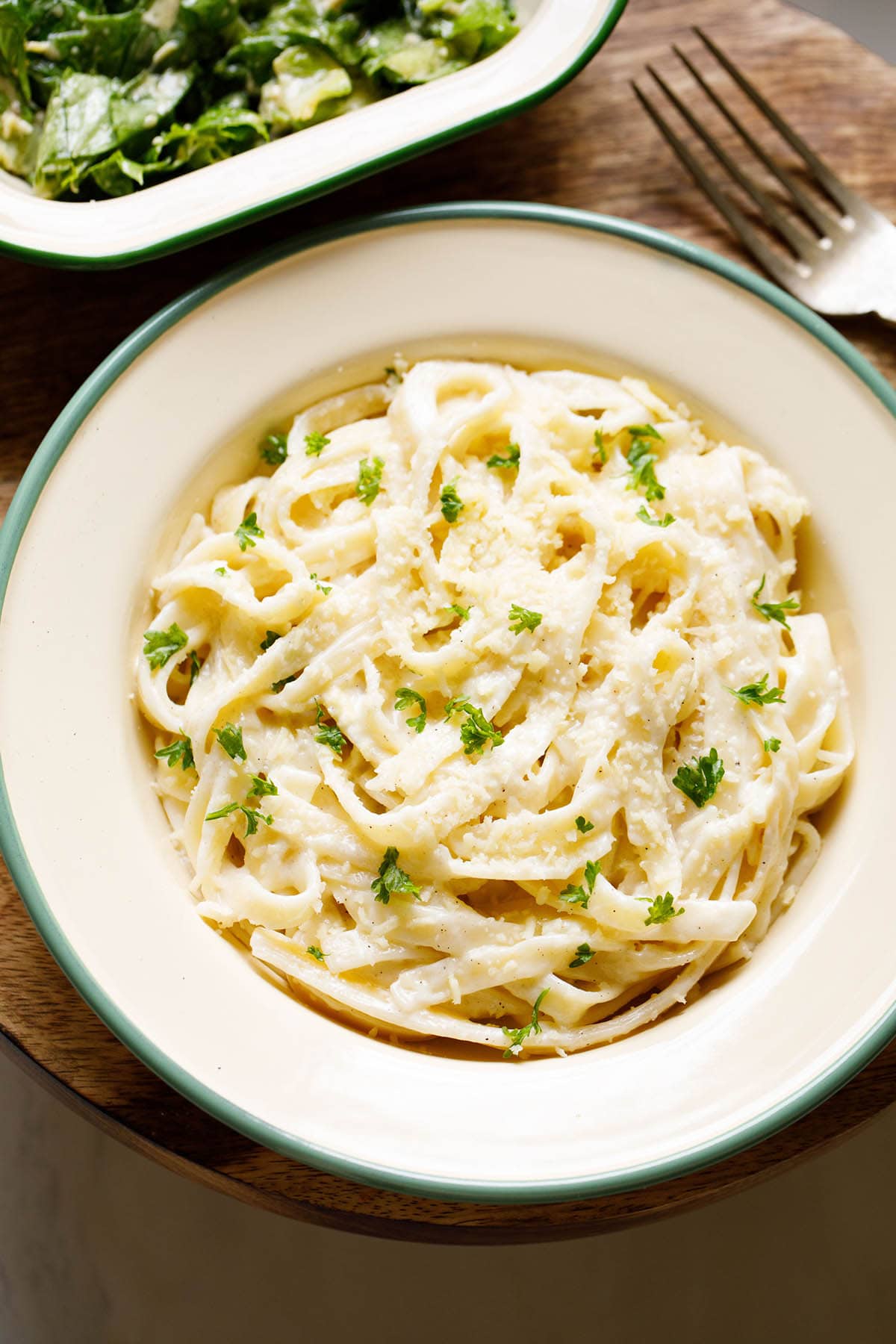 fettuccine alfredo sprinkled with grated parmesan and chopped parsley filled in a deep dish plate
