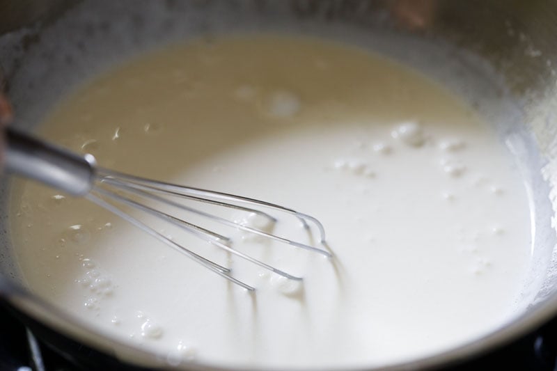 wired whisk inside the cream in pan