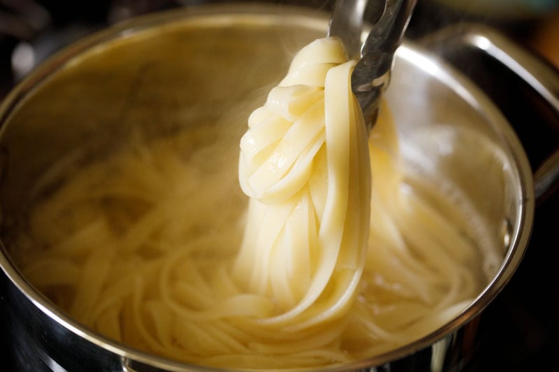 al dente fettuccine pasta lifted with pasta tongs