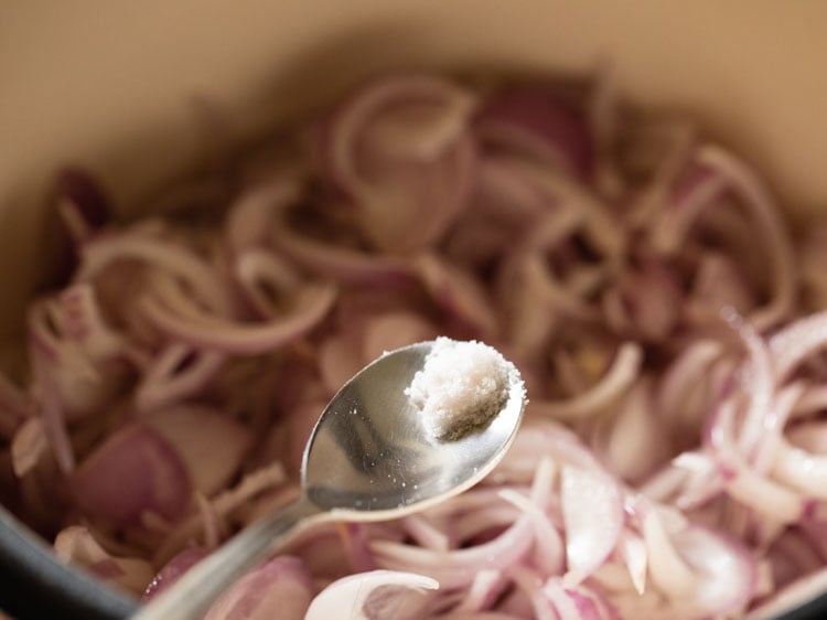 a pinch of salt being added to the onions
