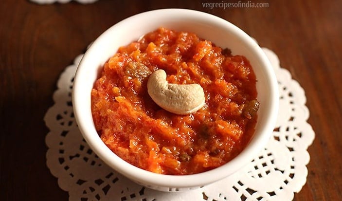 quick gajar ka halwa with khoya filled in a white bowl and garnished with one cashew placed on a paper doily