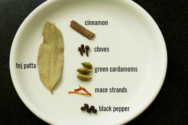 whole spices on a white plate with their names listed next to each 
