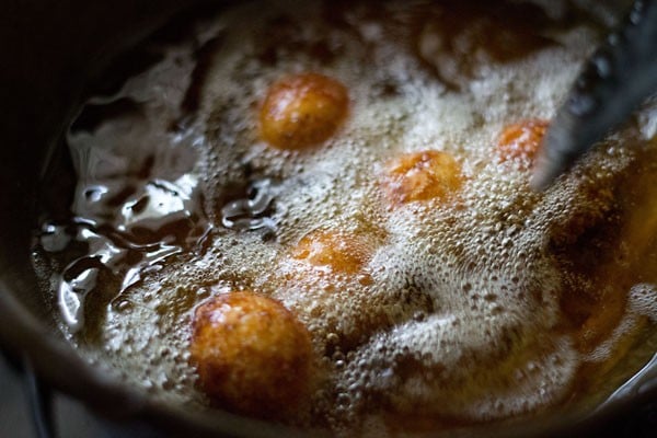 frying and turning the gulab jamun until golden