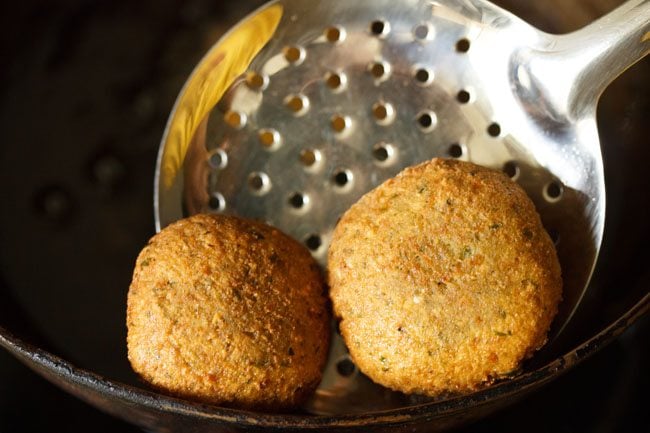 removing fried falafel with a slotted spoon
