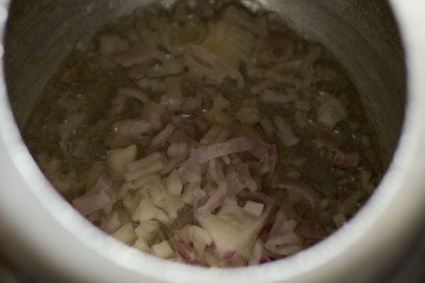onions added to hot oil in a pressure cooker