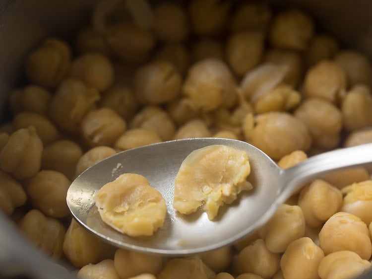 mashing cooked chickpeas with a spoon