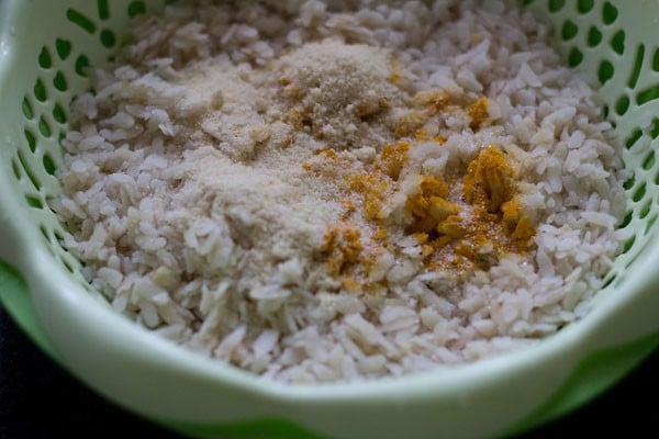 turmeric powder, sugar and salt added to poha in the colander. 