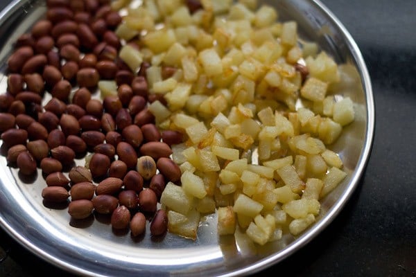potatoes and roasted peanuts on a steel plate ready for kanda batata poha. 