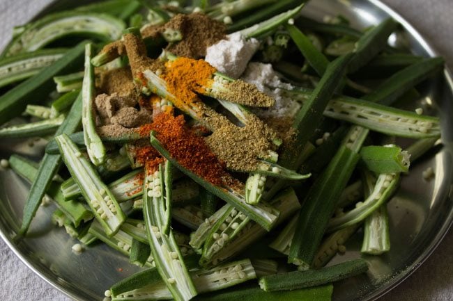 spice powders and salt added to sliced bhindi. 
