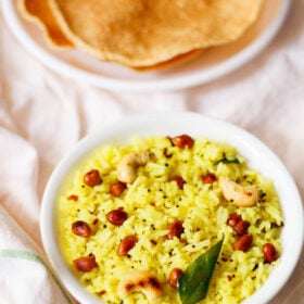 lemon rice served in a white bowl on a white cotton cloth with a side of fried papaddums
