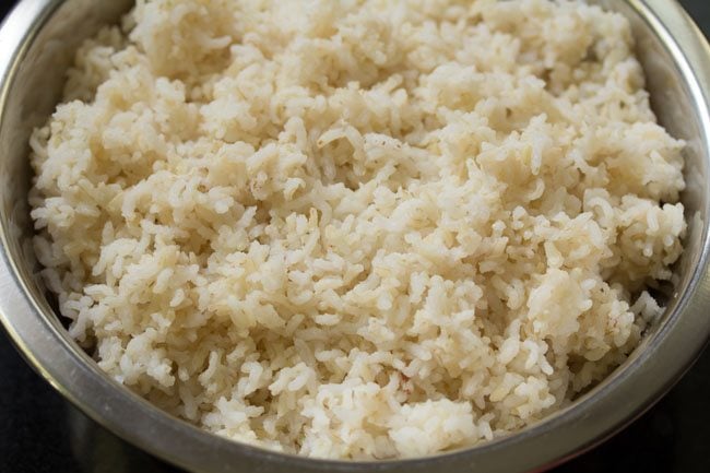 cooked rice in a steel bowl set aside to make lemon rice recipe
