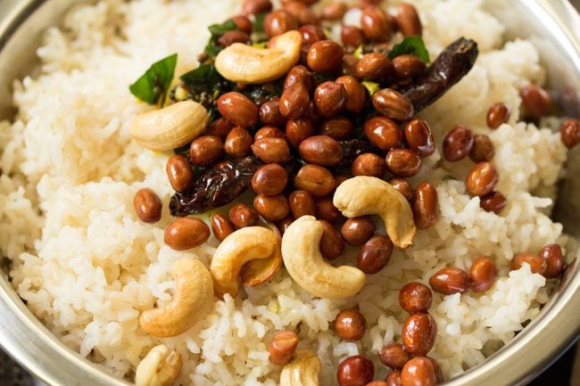 fried peanuts and cashews added to cooked rice in bowl to make lemon rice or chitranna