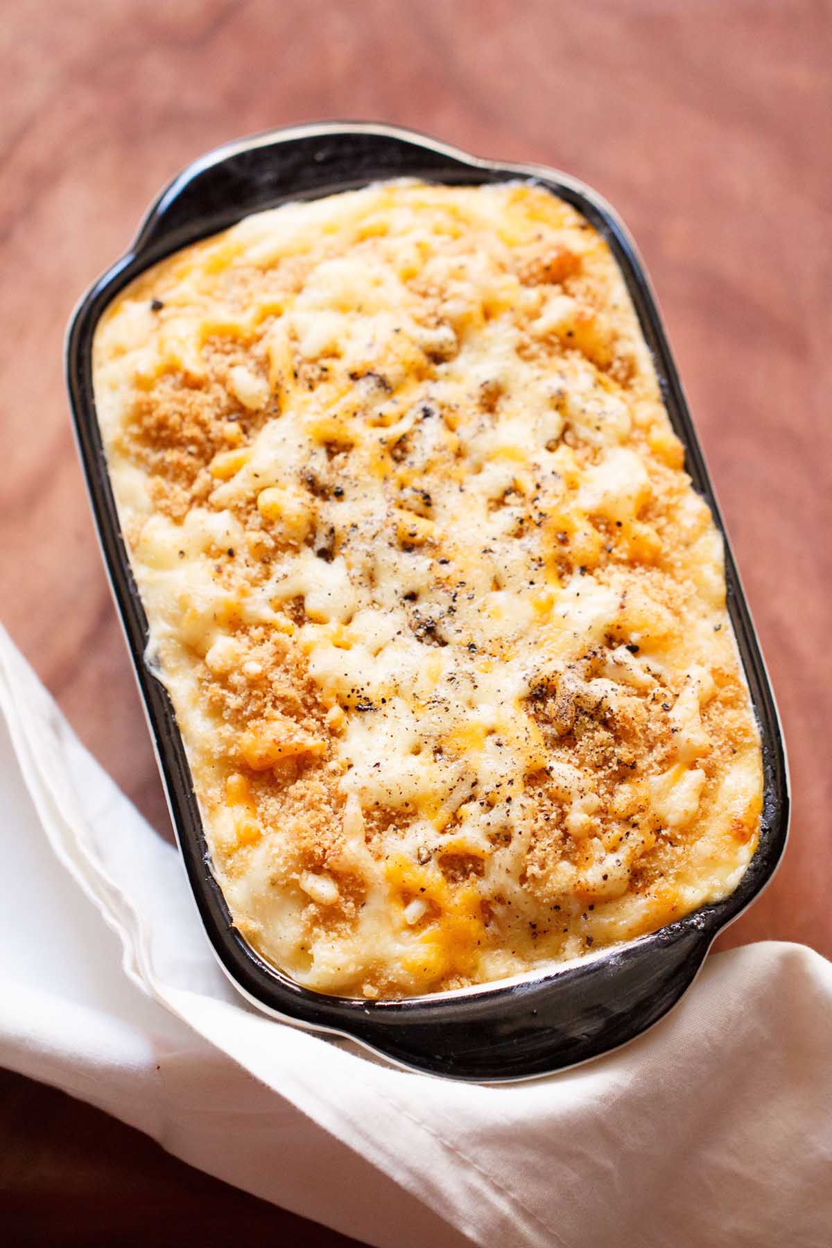 overhead hero shot of baked macaroni and cheese with breadcrumb topping on a wooden table. 