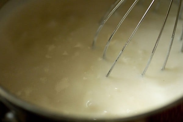 whisking the cheese sauce for mac and cheese as it cooks and thickens. 