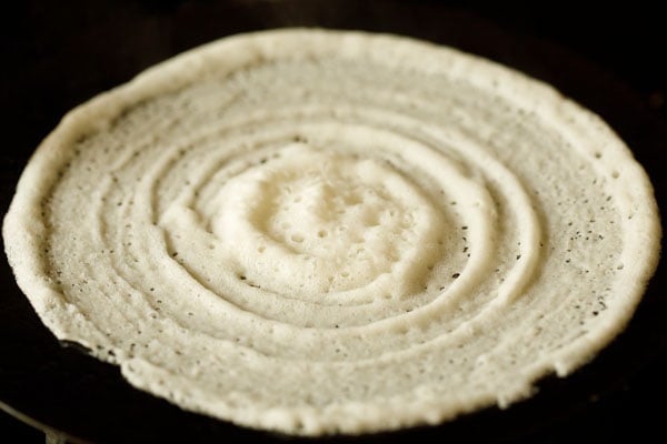 dosa batter spread neatly on tawa or skillet