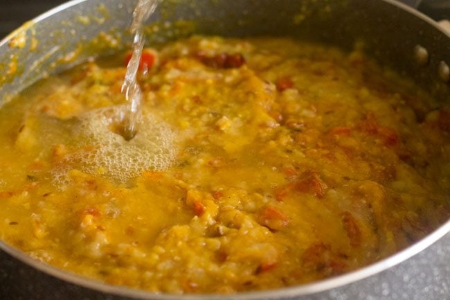 water being added to masoor dal in pan.