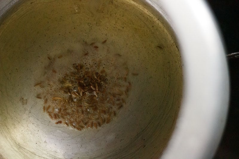Top shot of cumin seeds sautéing in pressure cooker