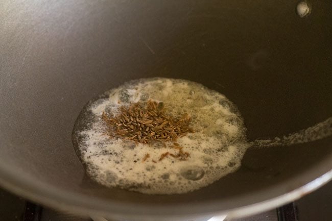 cumin seeds in oil and butter mixture in pan