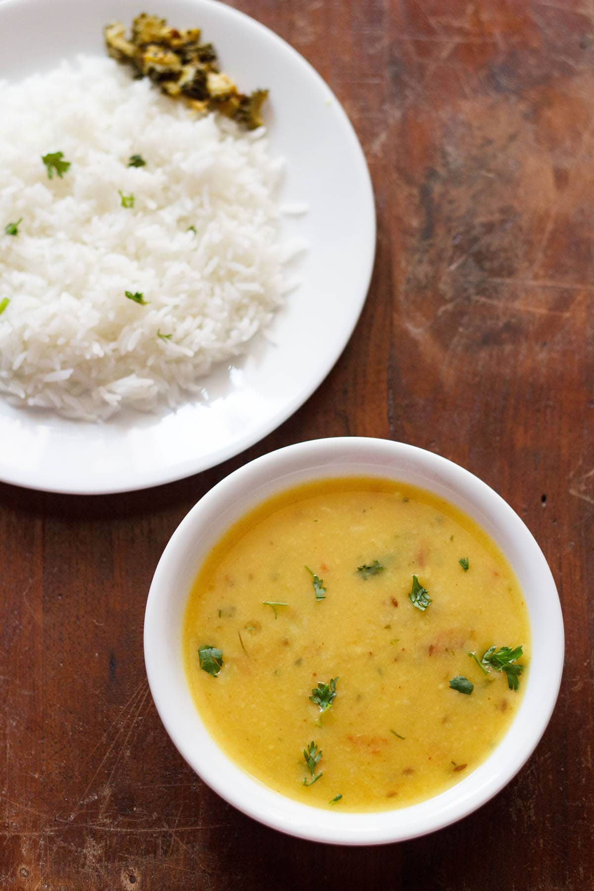 moong dal fry in white bowl with a side of steamed rice on a white plate