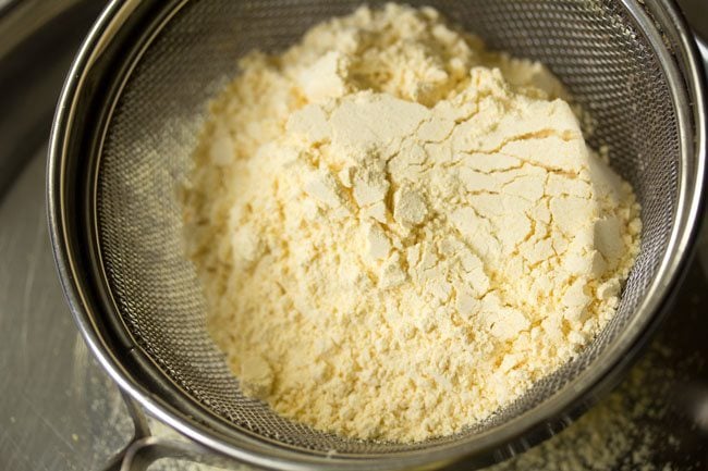 sifting besan chickpea flour through a mesh sieve