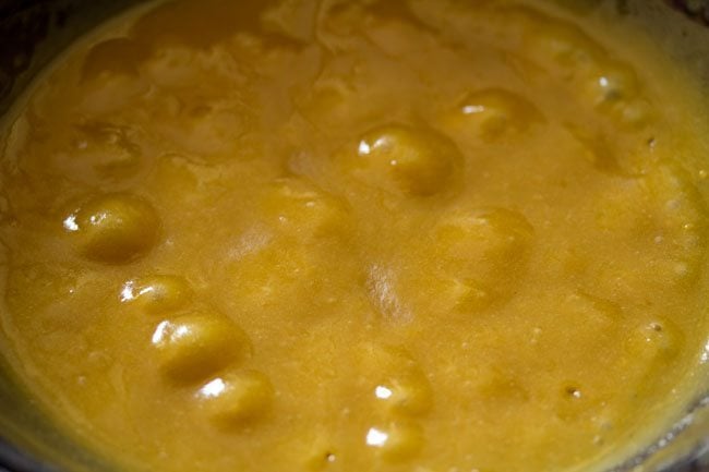 besan batter mixture for mysore pak recipe is clearly thicker with large bubbles and a dark golden color