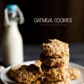 single oatmeal cookies kept on a white plate on a cream napkin with a small glass bottle of milk in the background