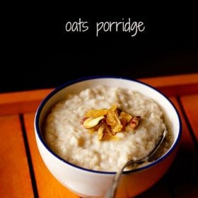 oats porridge topped with raisins and nuts in a blue rimmed white bowl with a spoon inside.
