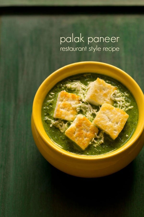 palak paneer filled in a yellow ceramic bowl topped with lightly golden paneer cubes and grated paneer with text layovers