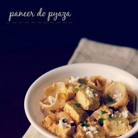 paneer do pyaza garnished with grated paneer and coriander leaves in a white bowl on a light beige napkin on a dark brown board and text layover.