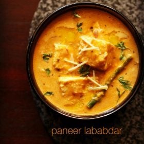 paneer lababdar served in a black bowl with ginger julienne on top and text layover.